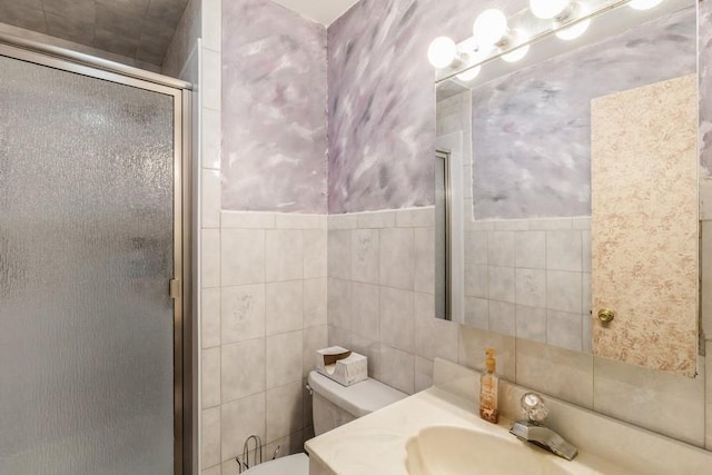 bathroom with vanity, toilet, a shower with door, and tile walls