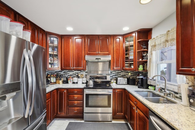 kitchen with stainless steel appliances, light stone countertops, sink, and backsplash