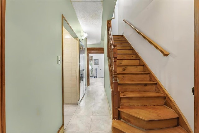 staircase with tile patterned floors and a textured ceiling