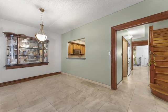 unfurnished dining area with a textured ceiling and light tile patterned floors