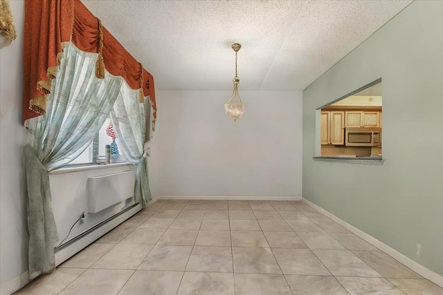 empty room with light tile patterned floors, a baseboard radiator, and a textured ceiling