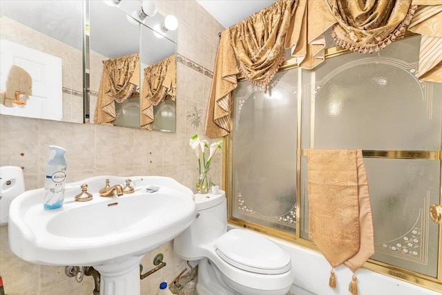 full bathroom featuring tasteful backsplash, sink, tile walls, shower / bath combination with glass door, and toilet