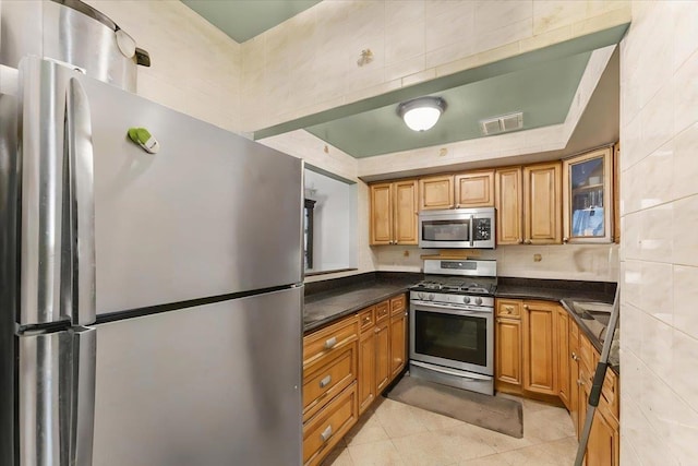 kitchen featuring appliances with stainless steel finishes, tile walls, and light tile patterned floors