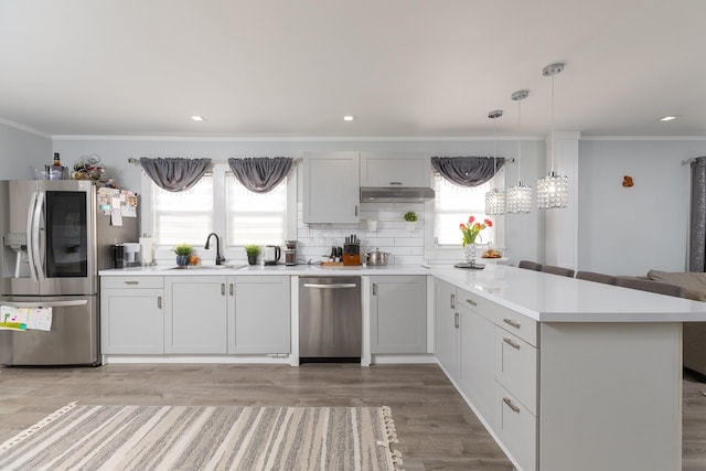 kitchen featuring sink, hanging light fixtures, ornamental molding, stainless steel appliances, and white cabinets
