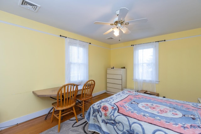 bedroom featuring multiple windows, hardwood / wood-style floors, and ceiling fan