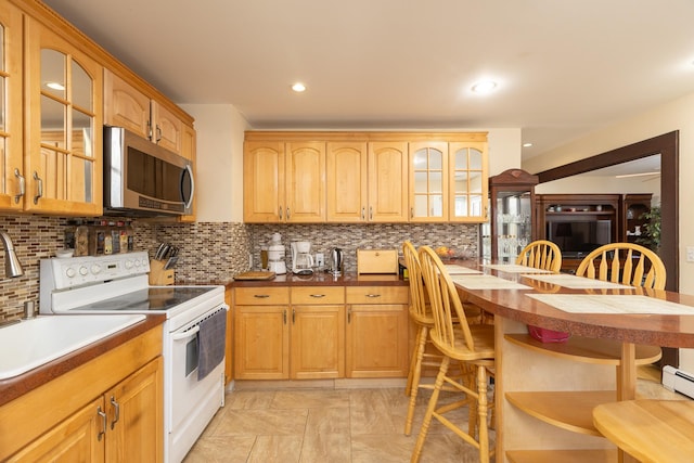 kitchen featuring sink, backsplash, electric range, and a kitchen breakfast bar