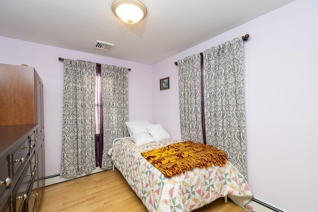 bedroom with a baseboard heating unit and hardwood / wood-style floors