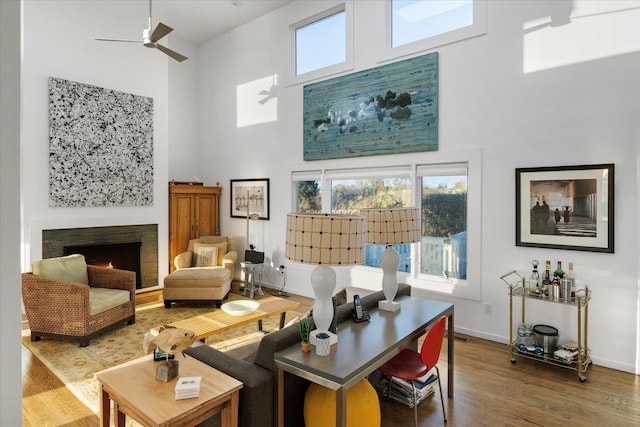 living room with hardwood / wood-style floors, a towering ceiling, and ceiling fan