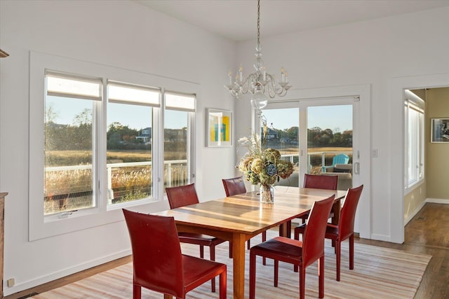 dining space featuring wood-type flooring and an inviting chandelier