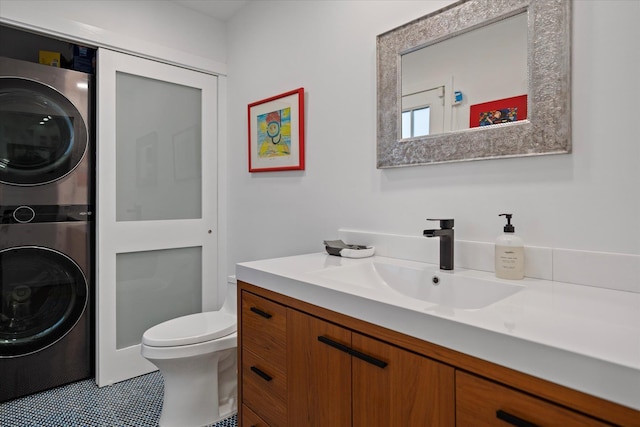 bathroom featuring vanity, toilet, and stacked washer / dryer