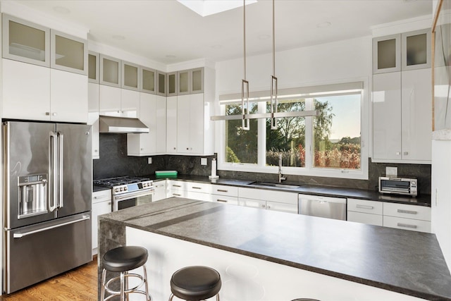 kitchen with white cabinetry, appliances with stainless steel finishes, sink, and a kitchen breakfast bar