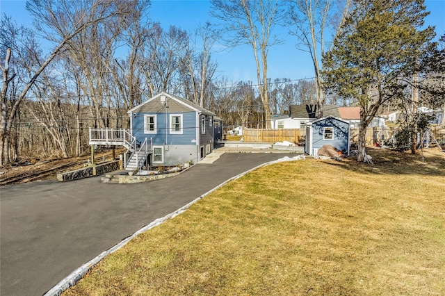 exterior space with an outbuilding, stairway, a front lawn, and a storage shed