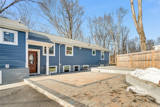 exterior space with roof with shingles, a patio area, and fence