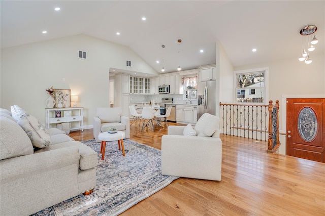 living area with high vaulted ceiling, recessed lighting, visible vents, and light wood-style flooring