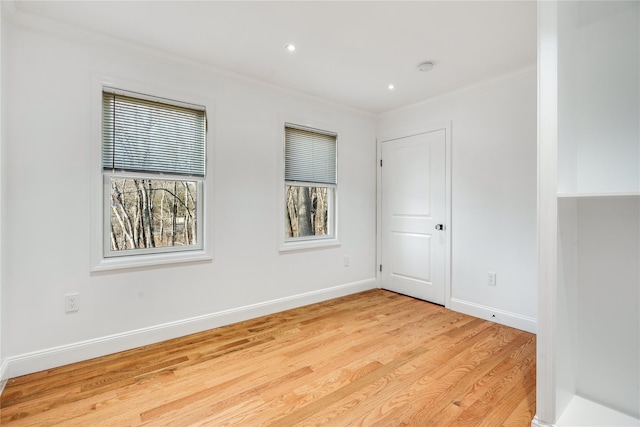 unfurnished room featuring ornamental molding, light wood finished floors, and baseboards