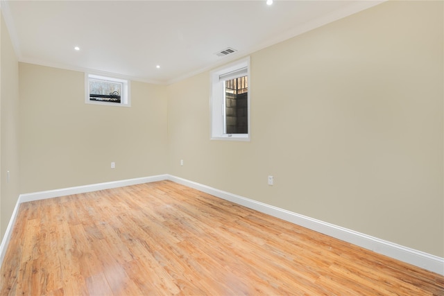 empty room featuring light wood-type flooring, baseboards, visible vents, and ornamental molding