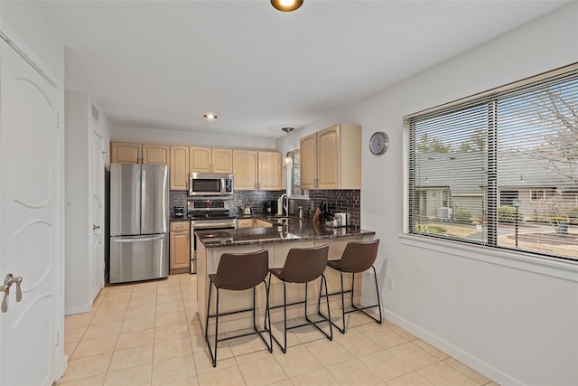 kitchen featuring light tile patterned floors, stainless steel appliances, a sink, light brown cabinetry, and tasteful backsplash