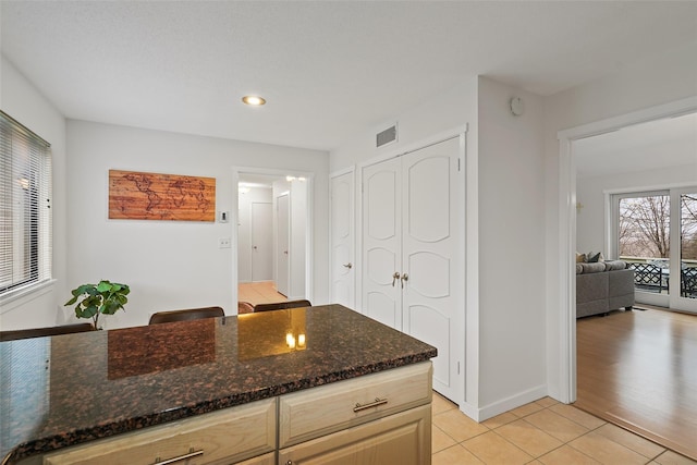 kitchen featuring dark stone counters, light tile patterned flooring, visible vents, and baseboards