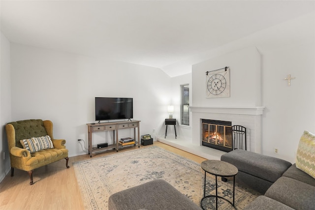 living area with lofted ceiling, wood finished floors, and a glass covered fireplace