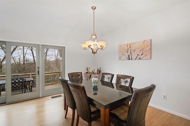 dining room with light wood-style floors, baseboards, visible vents, and a chandelier