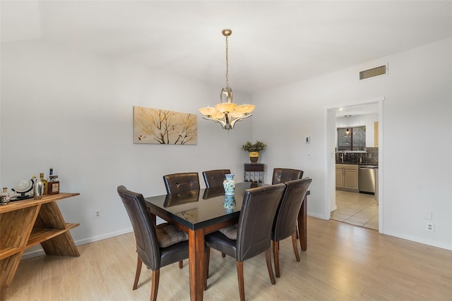 dining room with light wood-style flooring, visible vents, a chandelier, and baseboards