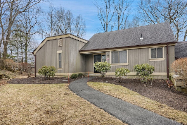 view of front of property featuring a front lawn and roof with shingles