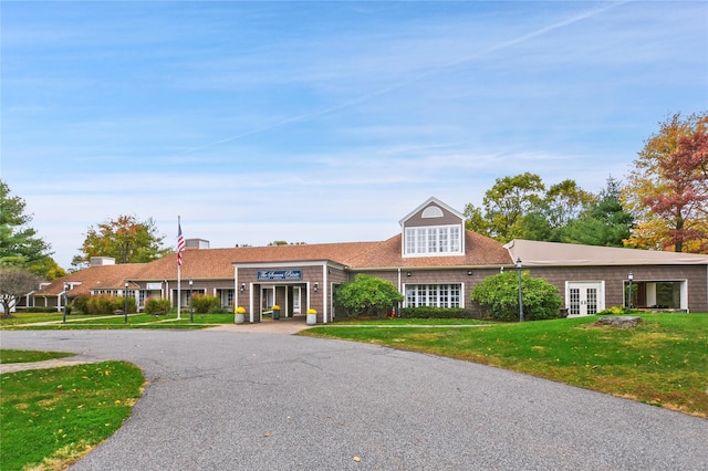 view of front of home with roof with shingles, french doors, and a front lawn