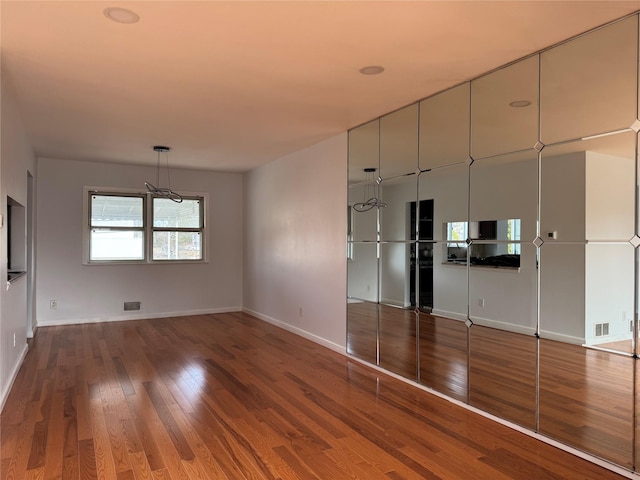 interior space with visible vents, baseboards, and hardwood / wood-style floors