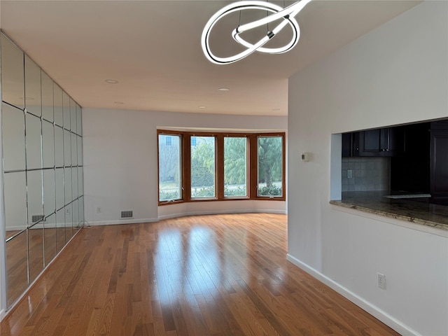 unfurnished living room featuring visible vents, baseboards, and wood finished floors