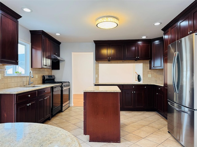 kitchen featuring range with gas stovetop, light tile patterned floors, a kitchen island, freestanding refrigerator, and a sink