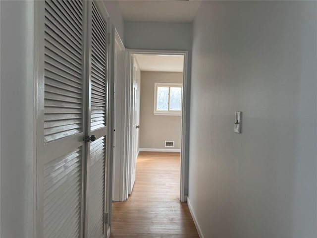 corridor featuring visible vents, baseboards, and wood finished floors