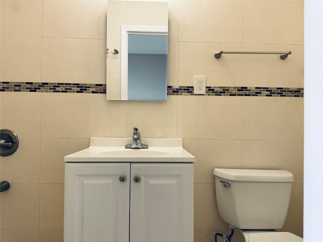 bathroom featuring toilet, vanity, and tile walls