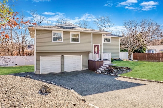 raised ranch featuring a garage and a front lawn