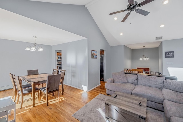 living room with high vaulted ceiling, ceiling fan with notable chandelier, and light hardwood / wood-style floors