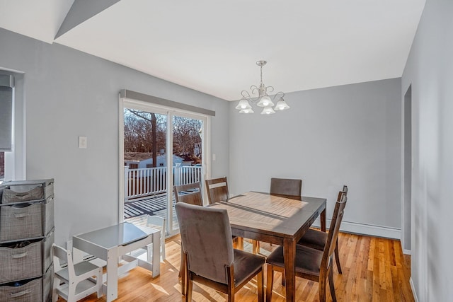 dining space with a baseboard heating unit, light hardwood / wood-style flooring, and a notable chandelier