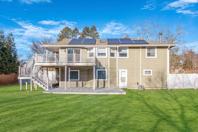 rear view of house with a lawn, a patio, a wooden deck, solar panels, and central air condition unit