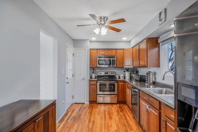 kitchen featuring stainless steel appliances, ceiling fan, sink, and light hardwood / wood-style floors