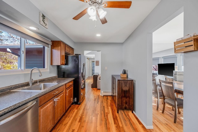 kitchen featuring sink, light wood-type flooring, appliances with stainless steel finishes, ceiling fan, and a baseboard heating unit