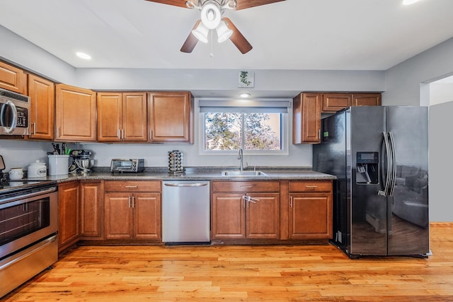 kitchen with ceiling fan, stainless steel appliances, light hardwood / wood-style floors, and sink