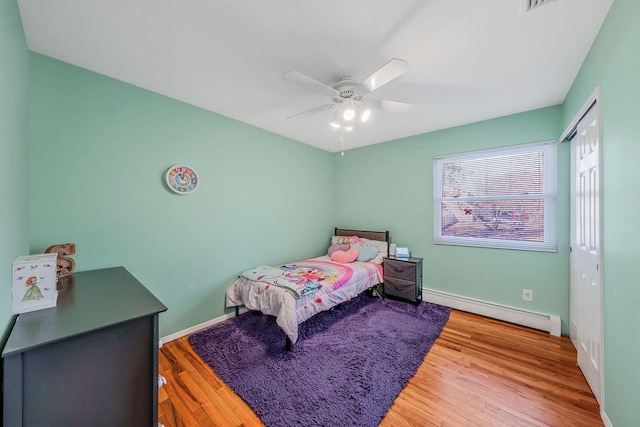 bedroom featuring hardwood / wood-style flooring, a closet, ceiling fan, and baseboard heating