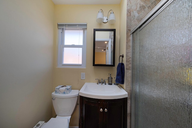 bathroom with a shower with door, vanity, and toilet