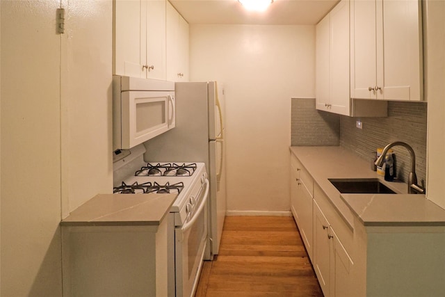 kitchen featuring white cabinetry, sink, decorative backsplash, light hardwood / wood-style floors, and white appliances