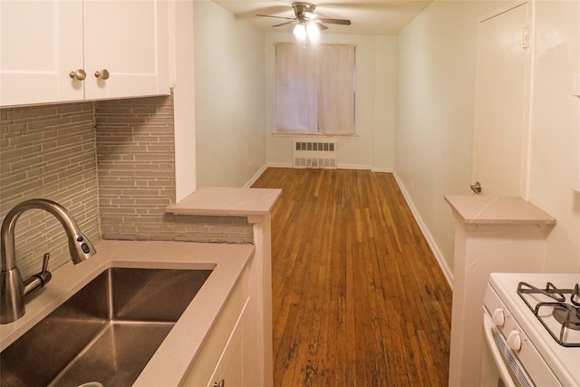 kitchen with white cabinetry, wood-type flooring, sink, backsplash, and ceiling fan