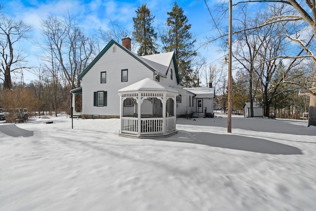 snow covered back of property with a gazebo