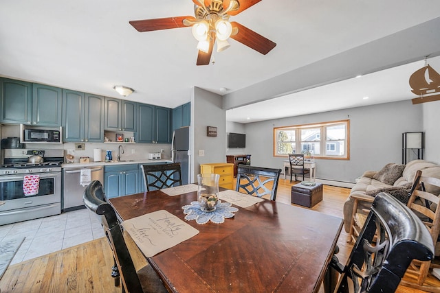 dining area with ceiling fan, sink, and light wood-type flooring