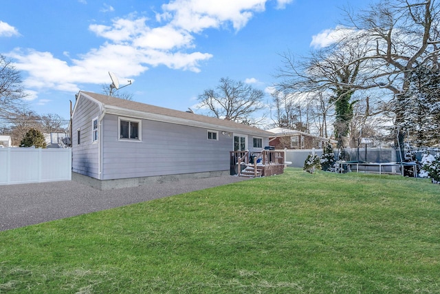 rear view of house featuring a trampoline and a lawn