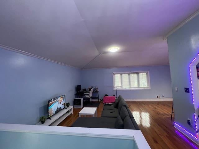 living room featuring hardwood / wood-style flooring, vaulted ceiling, and crown molding