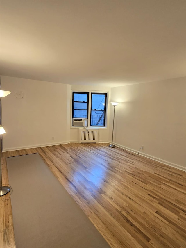 unfurnished living room with cooling unit, wood-type flooring, and radiator