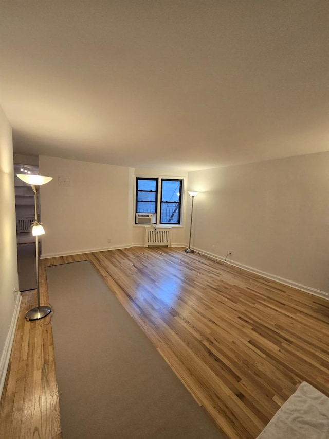 unfurnished living room with radiator heating unit and wood-type flooring