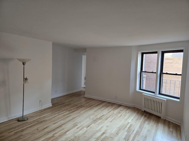 spare room featuring radiator and light hardwood / wood-style flooring